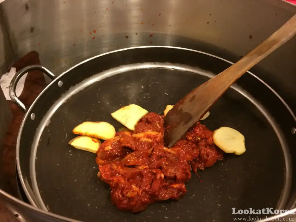 コチュジャンだれに漬けた鶏肉とさつまいもを丸い鉄板で焼き始めたタッカルビ
