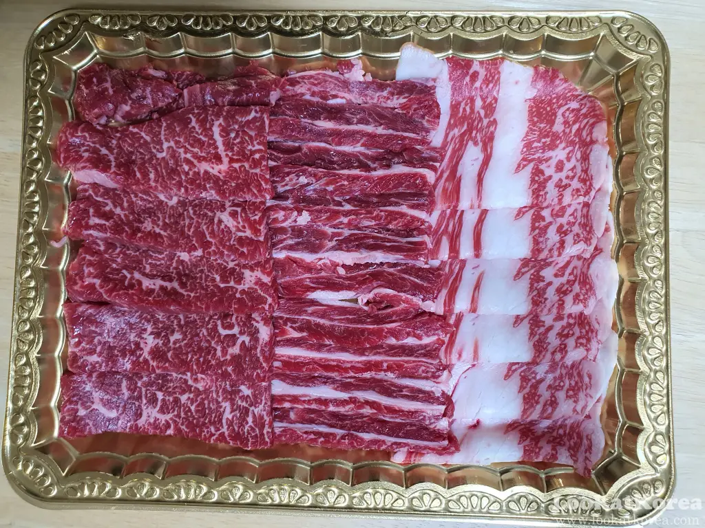 Assorted Hanwoo Korean beef cuts for grilling in a gold tray, sold at a Korean supermarket