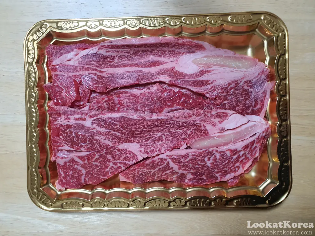 Well-marbled Hanwoo Korean beef sirloin (deungsim) in a gold tray, sold at a Korean supermarket